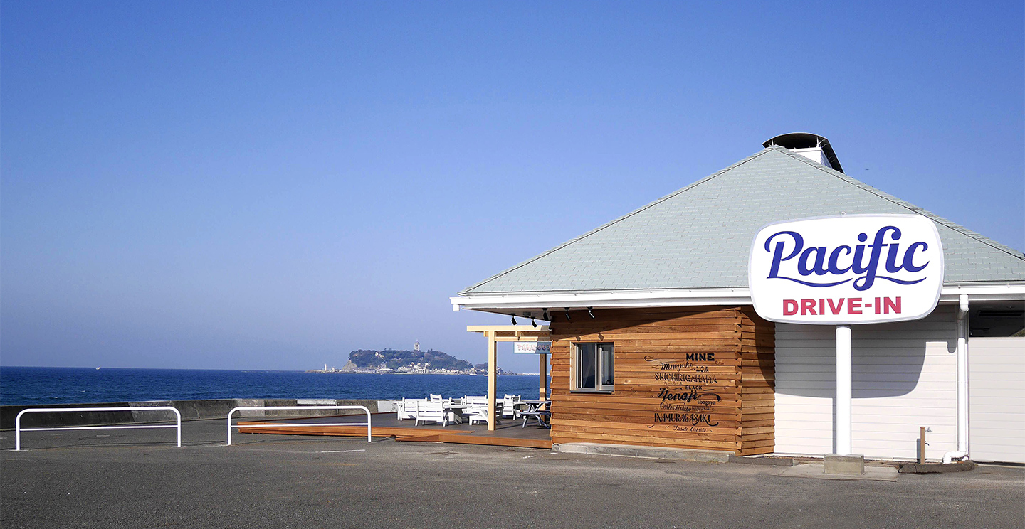 七里ヶ浜海岸駐車場に建つPacific DRIVE-INの外観と海